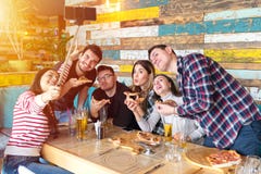 Jeunes amis gais prenant le selfie avec le téléphone intelligent tout en partageant une pizza au restaurant de barre images stock Jeunes amis gais prenant le selfie avec le téléphone intelligent tout en partageant une pizza au restaurant de barre images stock
