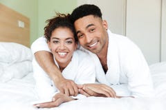 Jeunes couples affectueux africains heureux sur le lit Images stock Jeunes couples affectueux africains heureux sur le lit Images stock