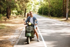Jeunes couples affectueux attrayants sur le scooter dehors Regard de côté photographie stock libre de droits Jeunes couples affectueux attrayants sur le scooter dehors Regard de côté photographie stock libre de droits