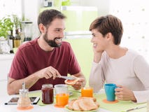 Jeunes couples affectueux prenant le petit déjeuner à la maison photographie stock Jeunes couples affectueux prenant le petit déjeuner à la maison photographie stock