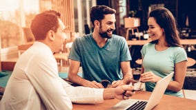 Jeunes couples consultant le vendeur de meubles photo stock Jeunes couples consultant le vendeur de meubles photo stock