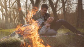 Jeunes couples dans l'amour une date par le feu Un type étreint une fille s'asseyant sur une couverture par le feu banque de vidéos Jeunes couples dans l'amour une date par le feu Un type étreint une fille s'asseyant sur une couverture par le feu banque de vidéos