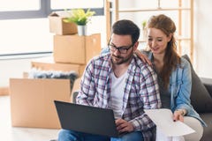 Jeunes couples déménageant la maison neuve Se reposer et détendre après déballage Recherche des idées sur l'ordinateur portable photos libres de droits Jeunes couples déménageant la maison neuve Se reposer et détendre après déballage Recherche des idées sur l'ordinateur portable photos libres de droits