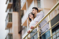 Jeunes couples embrassant et regardant loin appréciants des vues le coucher du soleil dans un balcon de nouveau hause images stock Jeunes couples embrassant et regardant loin appréciants des vues le coucher du soleil dans un balcon de nouveau hause images stock
