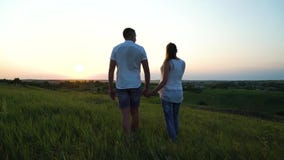 Jeunes couples enceintes heureux romantiques marchant dans la haute herbe au coucher du soleil banque de vidéos Jeunes couples enceintes heureux romantiques marchant dans la haute herbe au coucher du soleil banque de vidéos