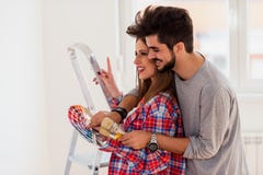 Jeunes couples gais choisissant la couleur pour la maison de peinture photographie stock Jeunes couples gais choisissant la couleur pour la maison de peinture photographie stock