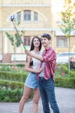 Jeunes couples heureux faisant le selfie par le téléphone portable intelligent dans la ville Photographie stock Jeunes couples heureux faisant le selfie par le téléphone portable intelligent dans la ville Photographie stock