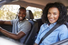 Jeunes couples noirs heureux conduisant dans une voiture souriant à l'appareil-photo photo stock Jeunes couples noirs heureux conduisant dans une voiture souriant à l'appareil-photo photo stock