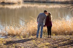 Jeunes couples occasionnels se tenant regardants le lac tenant des mains image libre de droits Jeunes couples occasionnels se tenant regardants le lac tenant des mains image libre de droits