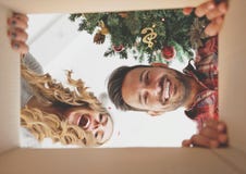 Jeunes couples ouvrant un cadeau de Noël image libre de droits Jeunes couples ouvrant un cadeau de Noël image libre de droits