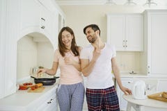 Jeunes couples préparant la nourriture dans la cuisine image libre de droits Jeunes couples préparant la nourriture dans la cuisine image libre de droits