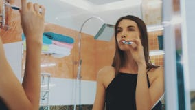 Jeunes dents de brosse de fille de brune, dansant devant le miroir dans la salle de bains Sourire clips vidéos Jeunes dents de brosse de fille de brune, dansant devant le miroir dans la salle de bains Sourire clips vidéos