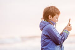 Jeunes heureux preeteen le garçon regardant le smth sur l'écran de téléphone, outdoo photo stock Jeunes heureux preeteen le garçon regardant le smth sur l'écran de téléphone, outdoo photo stock