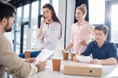 Jeunes hommes d'affaires discutant et faisant un brainstorm sur le lieu de travail dans le bureau de petite entreprise images stock Jeunes hommes d'affaires discutant et faisant un brainstorm sur le lieu de travail dans le bureau de petite entreprise images stock