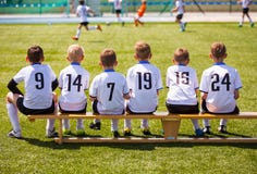 Jeunes joueurs de football Le jeune football Team Sitting sur le banc en bois photo libre de droits Jeunes joueurs de football Le jeune football Team Sitting sur le banc en bois photo libre de droits