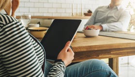Jeunes ménages mariés heureux dans la cuisine Une femme enceinte s'assied à une table et utilise une tablette Medias sociaux Photo stock Jeunes ménages mariés heureux dans la cuisine Une femme enceinte s'assied à une table et utilise une tablette Medias sociaux Photo stock