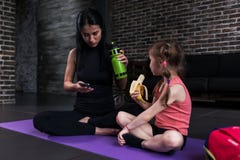 Joga dzieciaka instruktor i dziewczyna ma przerwę po tym jak treningu obsiadanie na matowym mieć przekąskę, woda pitna, używać te obraz stock Joga dzieciaka instruktor i dziewczyna ma przerwę po tym jak treningu obsiadanie na matowym mieć przekąskę, woda pitna, używać te obraz stock