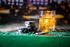 Jogando, conceito da fortuna, do jogo e do entretenimento - pr?ximo acima de microplaquetas do casino e de vidro do u?sque na tab imagem de stock royalty free Jogando, conceito da fortuna, do jogo e do entretenimento - pr?ximo acima de microplaquetas do casino e de vidro do u?sque na tab imagem de stock royalty free