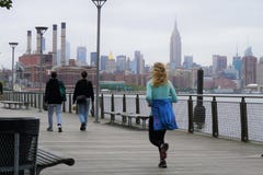 Jogger и ходоки на променаде в Бруклине с горизонтом NYC на заднем плане стоковое изображение Jogger и ходоки на променаде в Бруклине с горизонтом NYC на заднем плане стоковое изображение