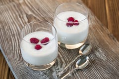 Jogurt z malinką na drewnianym szarość stole zdjęcie stock Jogurt z malinką na drewnianym szarość stole zdjęcie stock