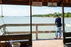 JOHOR, ΜΑΛΑΙΣΊΑ - ΤΟ ΦΕΒΡΟΥΆΡΙΟ ΤΟΥ 2019: Ένα άτομο που αλιεύει από το λιμενοβραχίονα στον ποταμό Johor στοκ φωτογραφίες JOHOR, ΜΑΛΑΙΣΊΑ - ΤΟ ΦΕΒΡΟΥΆΡΙΟ ΤΟΥ 2019: Ένα άτομο που αλιεύει από το λιμενοβραχίονα στον ποταμό Johor στοκ φωτογραφίες