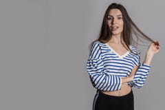 Jolie femme avec les cheveux pelucheux, habillés en passant contre un mur gris de studio photos stock Jolie femme avec les cheveux pelucheux, habillés en passant contre un mur gris de studio photos stock