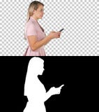Jolie femme dans le service de mini-messages rose de robe au téléphone intelligent, Alpha Channel photo stock Jolie femme dans le service de mini-messages rose de robe au téléphone intelligent, Alpha Channel photo stock