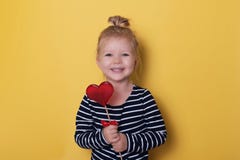 Jolie fille avec la sucrerie lumineuse rouge de lucette sur le fond jaune Photo libre de droits Jolie fille avec la sucrerie lumineuse rouge de lucette sur le fond jaune Photo libre de droits