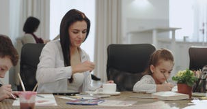 Jolie mère mûre avec beau travailler de trois enfants en ligne tout en faisant des devoirs avec ses enfants sur la cuisine clips vidéos Jolie mère mûre avec beau travailler de trois enfants en ligne tout en faisant des devoirs avec ses enfants sur la cuisine clips vidéos