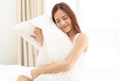 Jolis jeunes yeux asiatiques de femme de portrait fermés et étreignants l'oreiller dans le lit images libres de droits Jolis jeunes yeux asiatiques de femme de portrait fermés et étreignants l'oreiller dans le lit images libres de droits