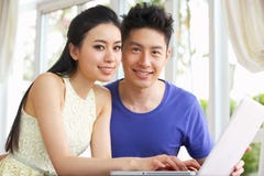 Jong Chinees Paar en thuis het Gebruiken van Laptop royalty-vrije stock fotografie Jong Chinees Paar en thuis het Gebruiken van Laptop royalty-vrije stock fotografie