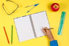 Jong geitjehand met open notitieboekje, pen, heerser, glazen en verse appel op gele achtergrond royalty-vrije stock afbeeldingen Jong geitjehand met open notitieboekje, pen, heerser, glazen en verse appel op gele achtergrond royalty-vrije stock afbeeldingen