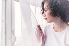 Jong meisje die aan het venster in de ochtend kijken Het concept peinzende eenzaamheid stock afbeeldingen Jong meisje die aan het venster in de ochtend kijken Het concept peinzende eenzaamheid stock afbeeldingen