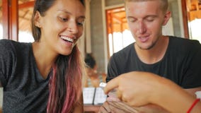 Jong Meisje die Vriendenbeelden op Mobiele Telefoonzitting tonen in Koffie thailand stock footage Jong Meisje die Vriendenbeelden op Mobiele Telefoonzitting tonen in Koffie thailand stock footage