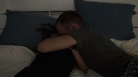 Jong paar die op bed in hun binnen hun bedsuits springen Zeldzame mening van het jonge gelukkige paar liggende omhelzen op modern stock videobeelden Jong paar die op bed in hun binnen hun bedsuits springen Zeldzame mening van het jonge gelukkige paar liggende omhelzen op modern stock videobeelden