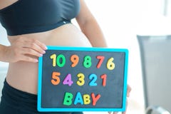 Jonge aanstaande moeder die met brievenblokken baby op haar zwangere buik spellen stock afbeelding Jonge aanstaande moeder die met brievenblokken baby op haar zwangere buik spellen stock afbeelding