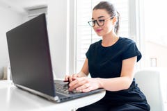 Jonge aantrekkelijke vrouw die aan laptop in moderne heldere flats werken stock foto's Jonge aantrekkelijke vrouw die aan laptop in moderne heldere flats werken stock foto's