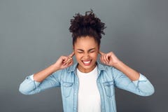 Jonge Afrikaanse die vrouw op de grijze toevallige dagelijkse levensstijl wordt geïsoleerd die van de muurstudio oren stoppen stock foto Jonge Afrikaanse die vrouw op de grijze toevallige dagelijkse levensstijl wordt geïsoleerd die van de muurstudio oren stoppen stock foto