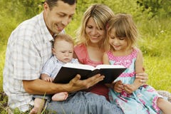 Jonge familie die de Bijbel in aard lezen royalty-vrije stock fotografie Jonge familie die de Bijbel in aard lezen royalty-vrije stock fotografie