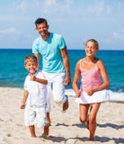 Jonge geitjes en vader het spelen op het strand royalty-vrije stock afbeelding Jonge geitjes en vader het spelen op het strand royalty-vrije stock afbeelding