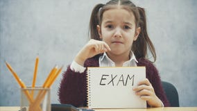 Jonge, hard-haired meisjeszitting bij de lijst Tijdens deze inschrijving in de handen van het examen stock video Jonge, hard-haired meisjeszitting bij de lijst Tijdens deze inschrijving in de handen van het examen stock video