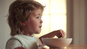 Jonge jong geitjezitting op de lijst die gezond voedsel met grappige uitdrukking op gezicht eten Het eten van het jonge geitje La stock video Jonge jong geitjezitting op de lijst die gezond voedsel met grappige uitdrukking op gezicht eten Het eten van het jonge geitje La stock video