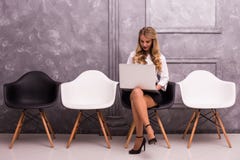 Jonge laptop van de onderneemsterholding terwijl het zitten op stoel stock fotografie Jonge laptop van de onderneemsterholding terwijl het zitten op stoel stock fotografie