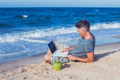 Jonge mensenzitting op strand met laptop royalty-vrije stock fotografie Jonge mensenzitting op strand met laptop royalty-vrije stock fotografie
