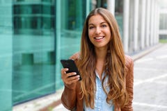 Jonge mooie onderneemster die en camera glimlachen bekijken terwijl het houden van mobiele telefoon in haar hand Bedrijfs concept stock afbeeldingen Jonge mooie onderneemster die en camera glimlachen bekijken terwijl het houden van mobiele telefoon in haar hand Bedrijfs concept stock afbeeldingen