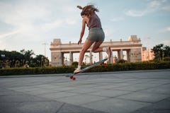 Jonge sportieve vrouw die op longboard in het park berijden stock afbeelding Jonge sportieve vrouw die op longboard in het park berijden stock afbeelding