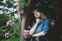 Jonge vrouw dichtbij struik van purpere bloemen in een tuin stock fotografie Jonge vrouw dichtbij struik van purpere bloemen in een tuin stock fotografie