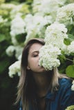 Jonge vrouw dichtbij struik van witte bloemen in een tuin stock afbeelding Jonge vrouw dichtbij struik van witte bloemen in een tuin stock afbeelding