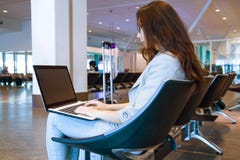 Jonge vrouw die laptop op overlapping het typen toetsenbord binnen in luchthaven houden stock foto's Jonge vrouw die laptop op overlapping het typen toetsenbord binnen in luchthaven houden stock foto's