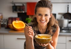 Jonge vrouw die pompoensoep in keuken eten royalty-vrije stock foto Jonge vrouw die pompoensoep in keuken eten royalty-vrije stock foto
